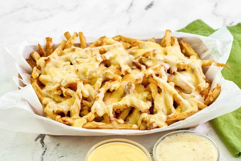Copycat Wingstop Louisiana voodoo fries and small bowls of ranch and cheese sauce by it.