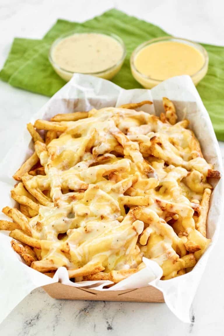 Copycat Wingstop Louisiana voodoo fires in a serving basket and sauces behind it.