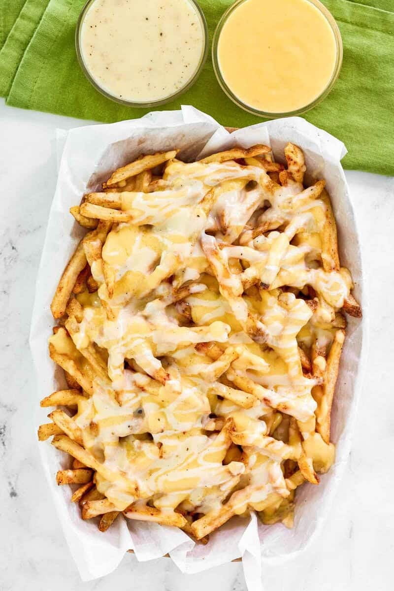 Copycat Wingstop Louisiana voodoo fries and bowls of cheese sauce and ranch dressing.