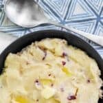 A large bowl of homemade Cheesecake Factory mashed potatoes and a serving spoon.