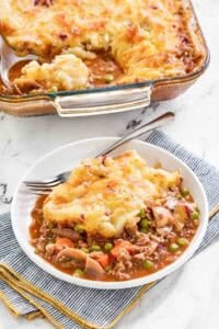 Copycat Cheesecake Factory shepherd's pie serving on a plate and the pie in a baking dish.