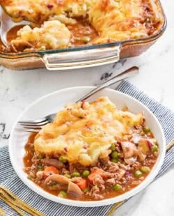 Copycat Cheesecake Factory shepherd's pie serving on a plate and the pie in a baking dish.
