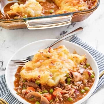 Copycat Cheesecake Factory shepherd's pie serving on a plate and the pie in a baking dish.