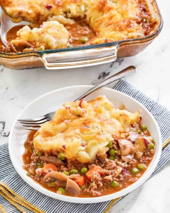 Copycat Cheesecake Factory shepherd's pie serving on a plate and the pie in a baking dish.
