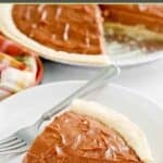 Homemade chocolate cream pie slice and a fork on a plate and the pie behind it.