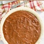 A whole homemade chocolate cream pie on a wood surface.