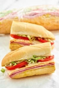 Copycat Kmart sub sandwich cut in half and another behind it wrapped in plastic.