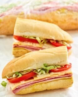 Copycat Kmart sub sandwich cut in half and another behind it wrapped in plastic.