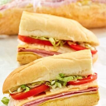 Copycat Kmart sub sandwich cut in half and another behind it wrapped in plastic.