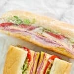 Homemade Kmart sub sandwiches - one wrapped in plastic and one cut in half.