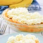 A slice of copycat Marie Callender's banana cream pie on a plate and the pie behind it.