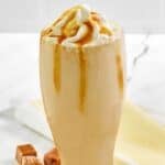 Homemade McDonald's caramel frappe in a tall glass on a marble surface.