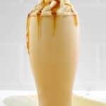 Homemade McDonald's caramel frappe in a tall glass and caramels beside it.