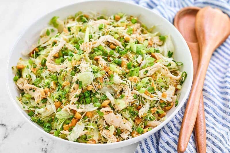 Copycat Ming's Thai chicken salad in a large bowl and salad servers beside it.