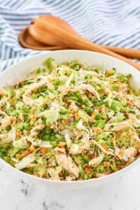 Copycat Ming's Thai chicken salad in a serving bowl and wooden salad servers behind it.