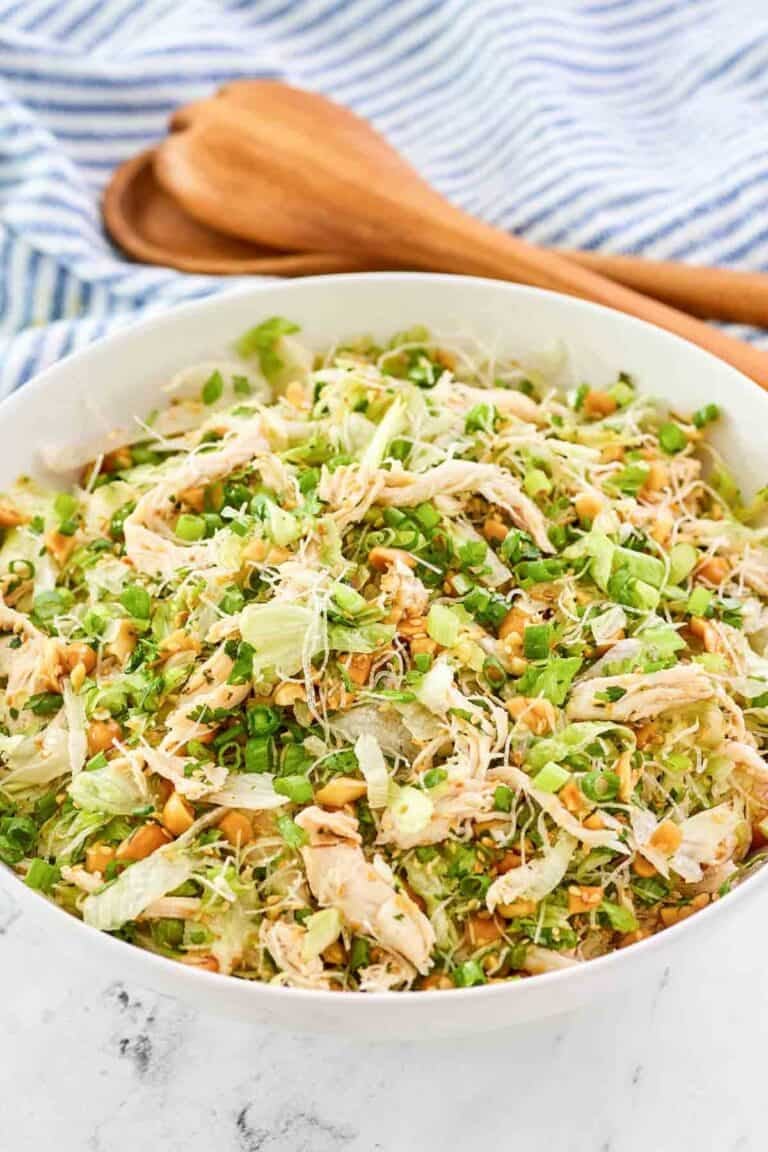 Copycat Ming's Thai chicken salad in a serving bowl and wooden salad servers behind it.