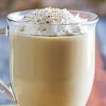 Homemade Starbucks eggnog latte topped with whipped cream in a glass coffee mug.
