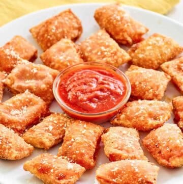 Copycat Totino's pepperoni pizza rolls and a cups of marinara on a platter.
