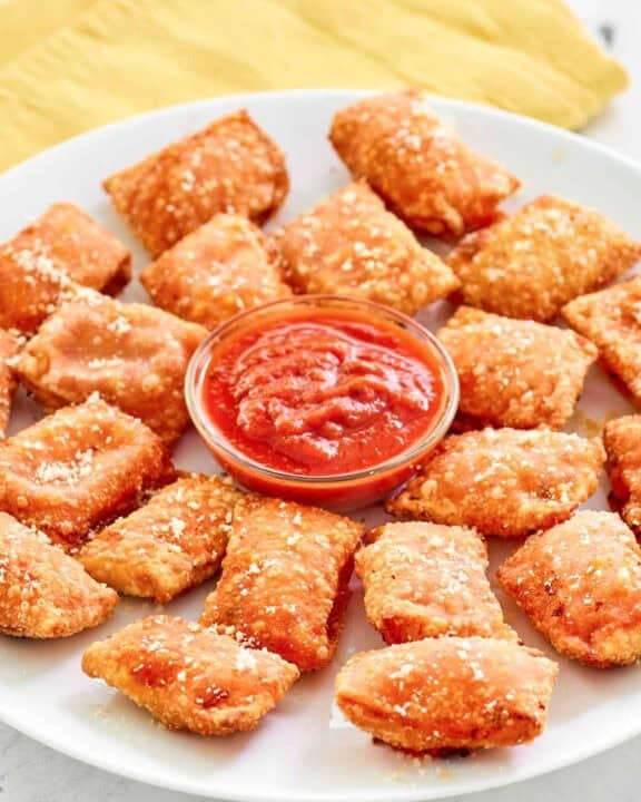 Copycat Totino's pepperoni pizza rolls and a cups of marinara on a platter.