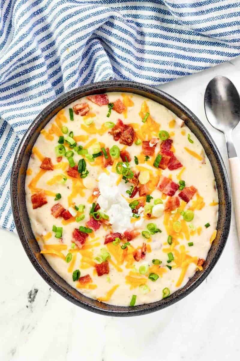 Copycat Black Angus Steakhouse baked potato soup and a spoon next to it.