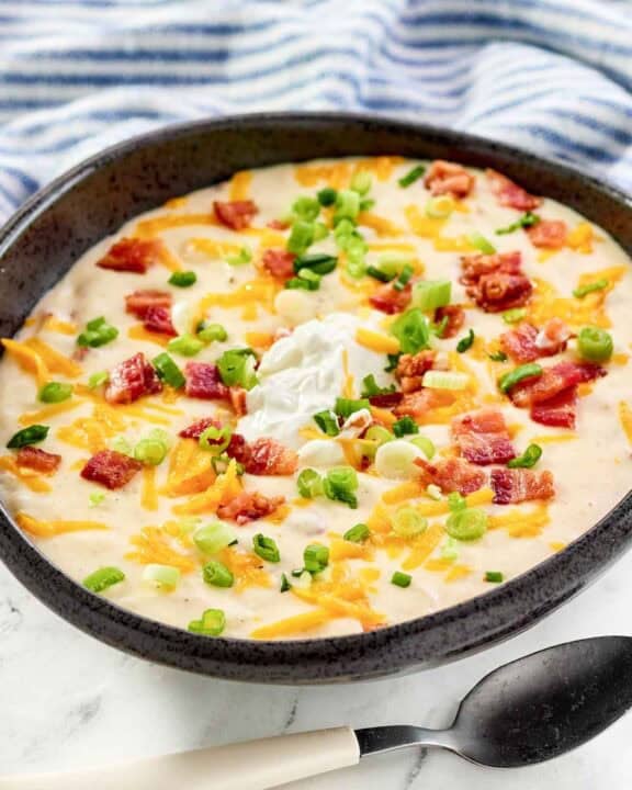 Copycat Black Angus Steakhouse baked potato soup and a spoon in front of it.