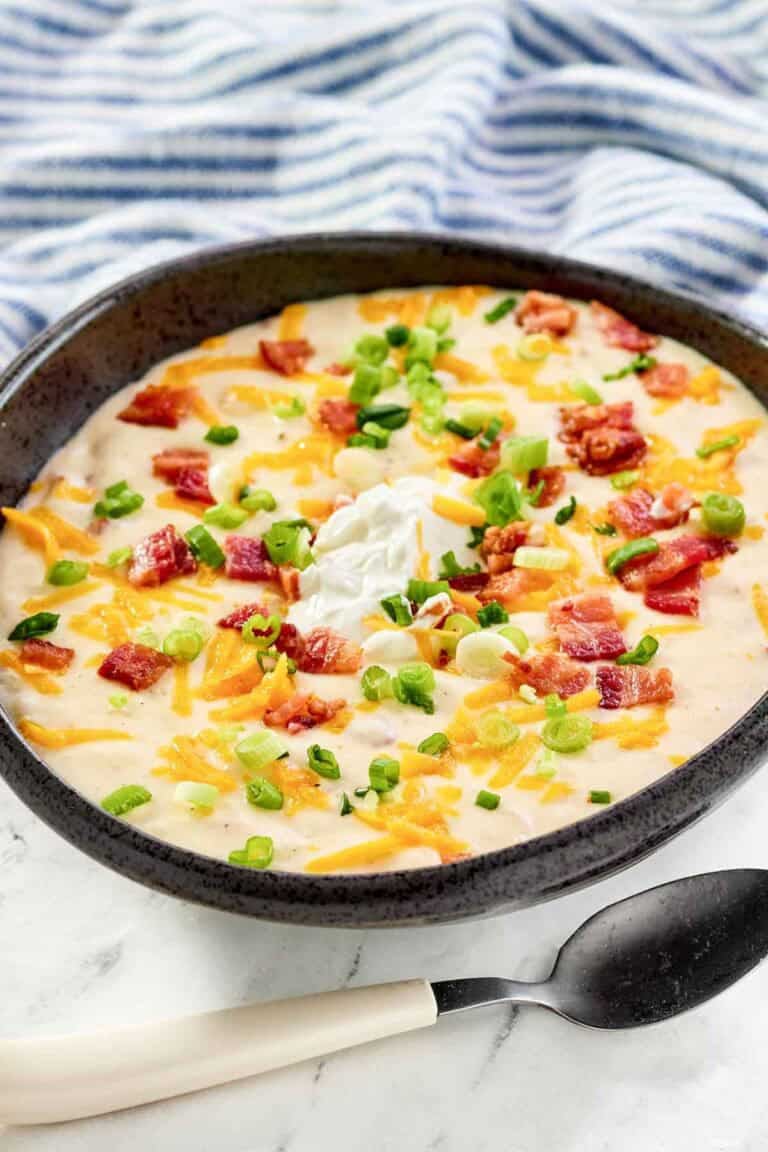 Copycat Black Angus Steakhouse baked potato soup and a spoon in front of it.