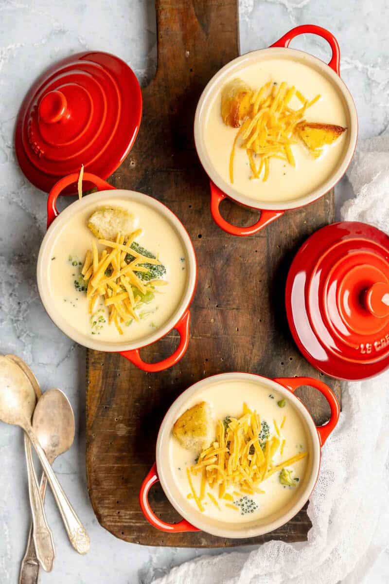 Three bowls of copycat Black-eyed Pea broccoli cheese soup on a wooden serving board.