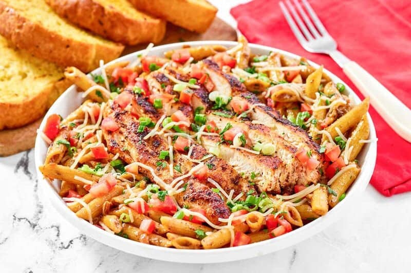 Copycat Chili's cajun chicken pasta, garlic bread behind it, and a fork beside it.