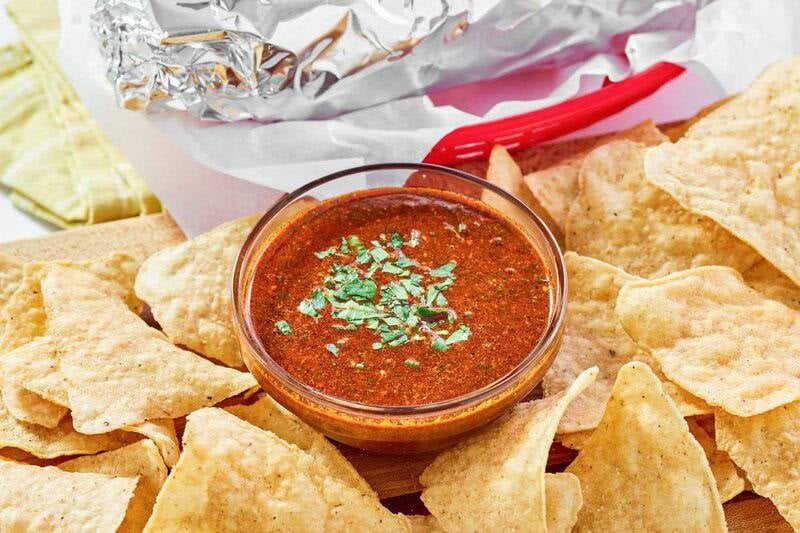 Copycat Chipotle Mexican Grill red chimichurri sauce in a small bowl, tortilla chips, and a burrito.