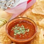 Copycat Chipotle Mexican Grill red chimichurri sauce served with chips and a burrito.