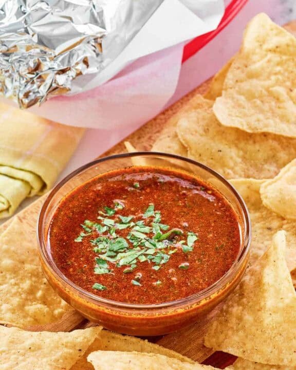 Copycat Chipotle Mexican Grill red chimichurri sauce served with chips and a burrito.