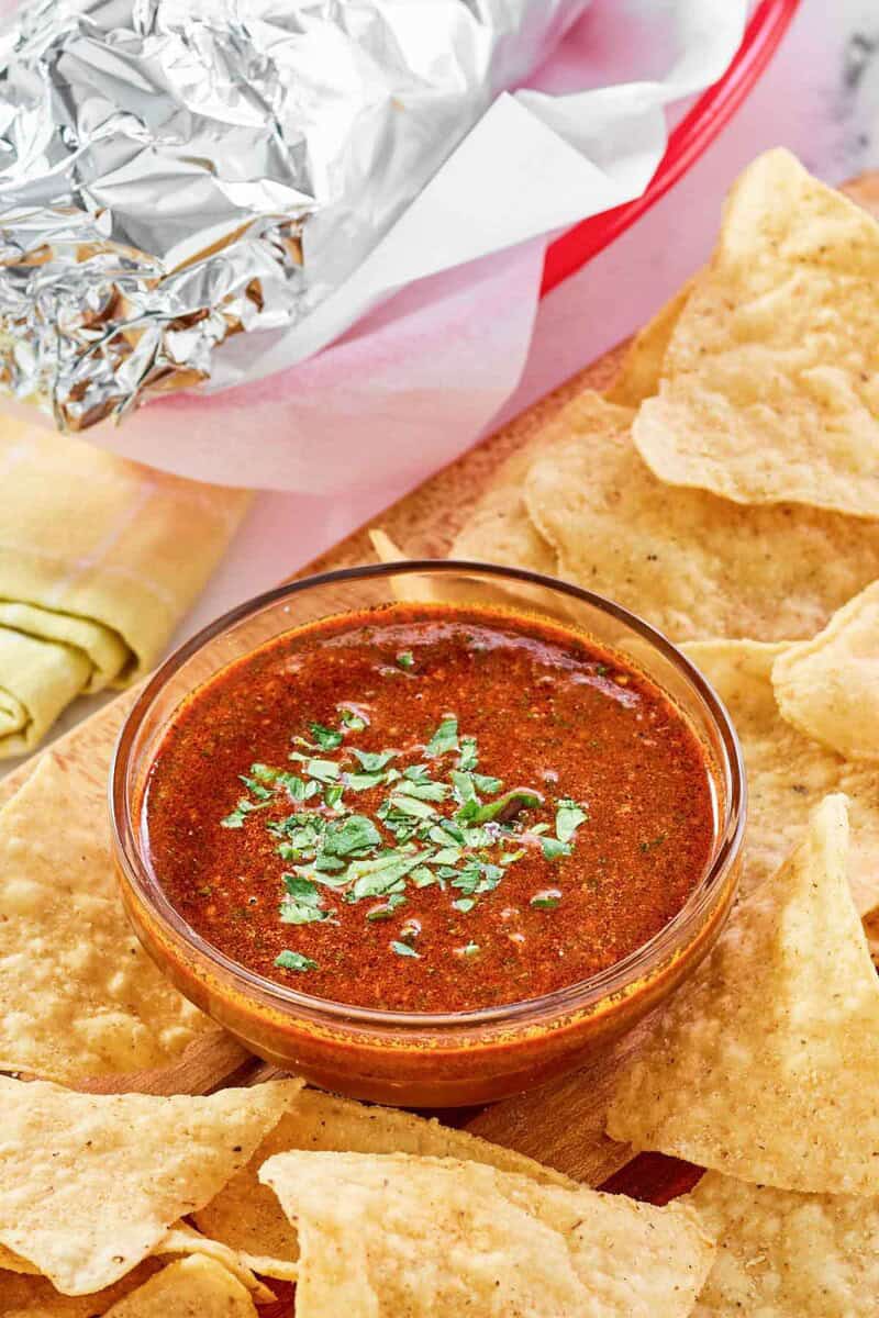 Copycat Chipotle Mexican Grill red chimichurri sauce served with chips and a burrito.