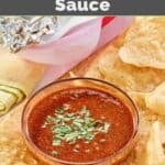 Homemade Chipotle red chimichurri sauce served with tortilla chips on a wooden tray.