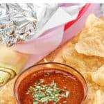 Homemade Chipotle red chimichurri sauce in a small bowl surrounded with tortilla chips.