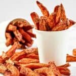 Copycat Five Guys Cajun fries served in large cups and on parchment paper.