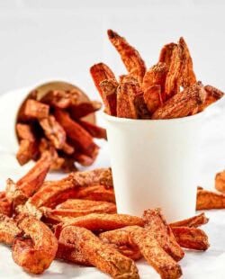Copycat Five Guys Cajun fries served in large cups and on parchment paper.