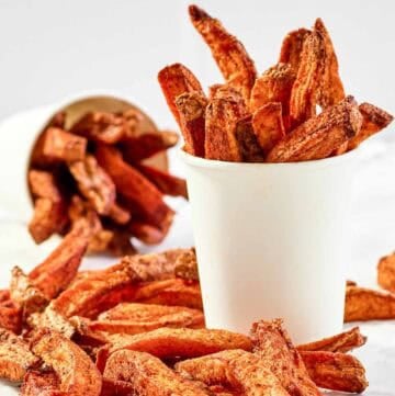 Copycat Five Guys Cajun fries served in large cups and on parchment paper.