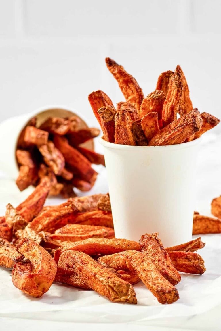 Copycat Five Guys Cajun fries served in large cups and on parchment paper.