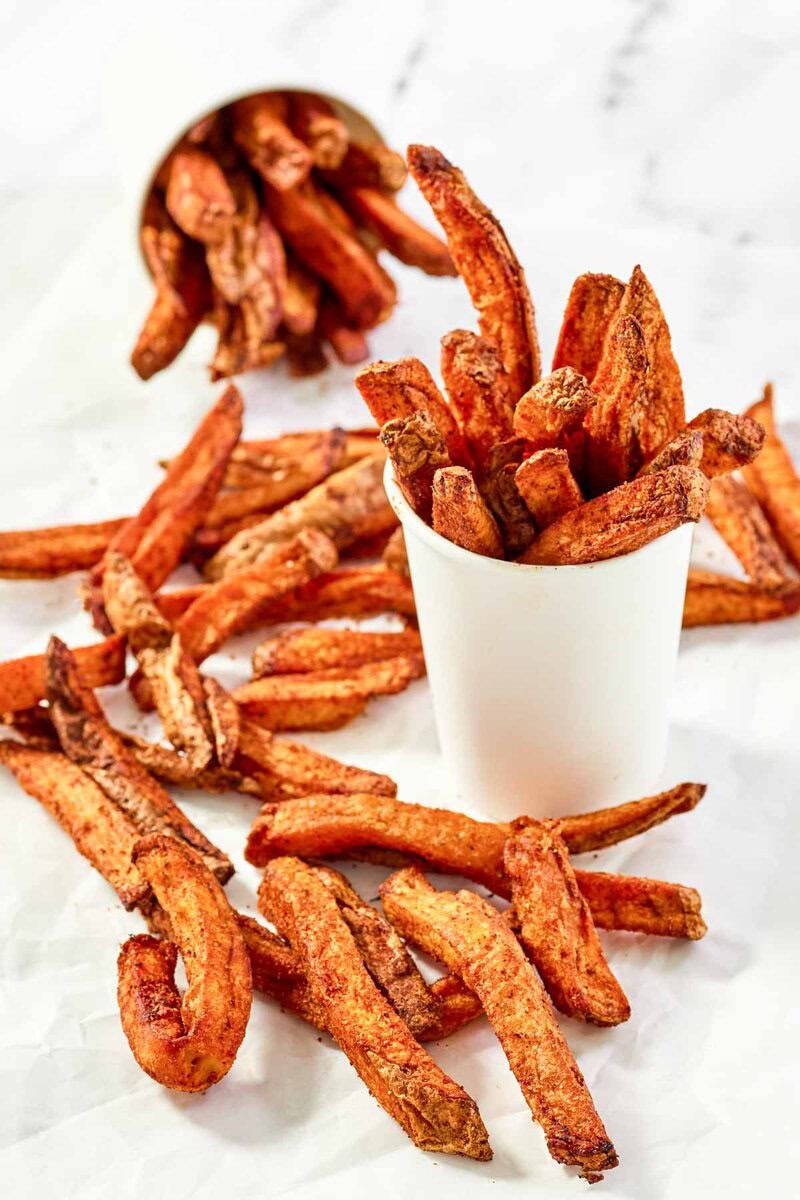 Copycat Five Guys Cajun fries in large cups and scattered around them.