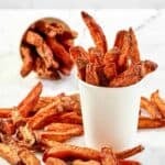 Homemade Five Guys Cajun fries in two serving cups and scattered around them.