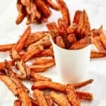 Homemade Five Guys Cajun fries in paper cups and scattered next to them.