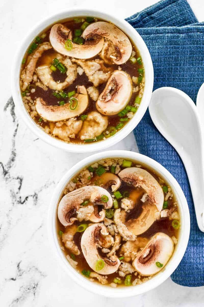 Two bowls of homemade Japanese clear soup on a marble surface.