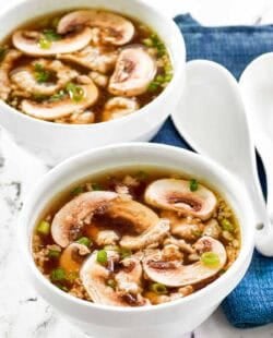 Homemade Japanese clear soup in two bowls and two soup spoons beside them.