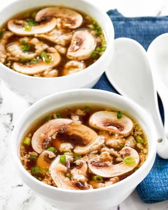 Homemade Japanese clear soup in two bowls and two soup spoons beside them.