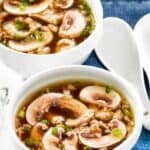 Two bowls of homemade Japanese clear soup and two soup spoons on a cloth napkin.