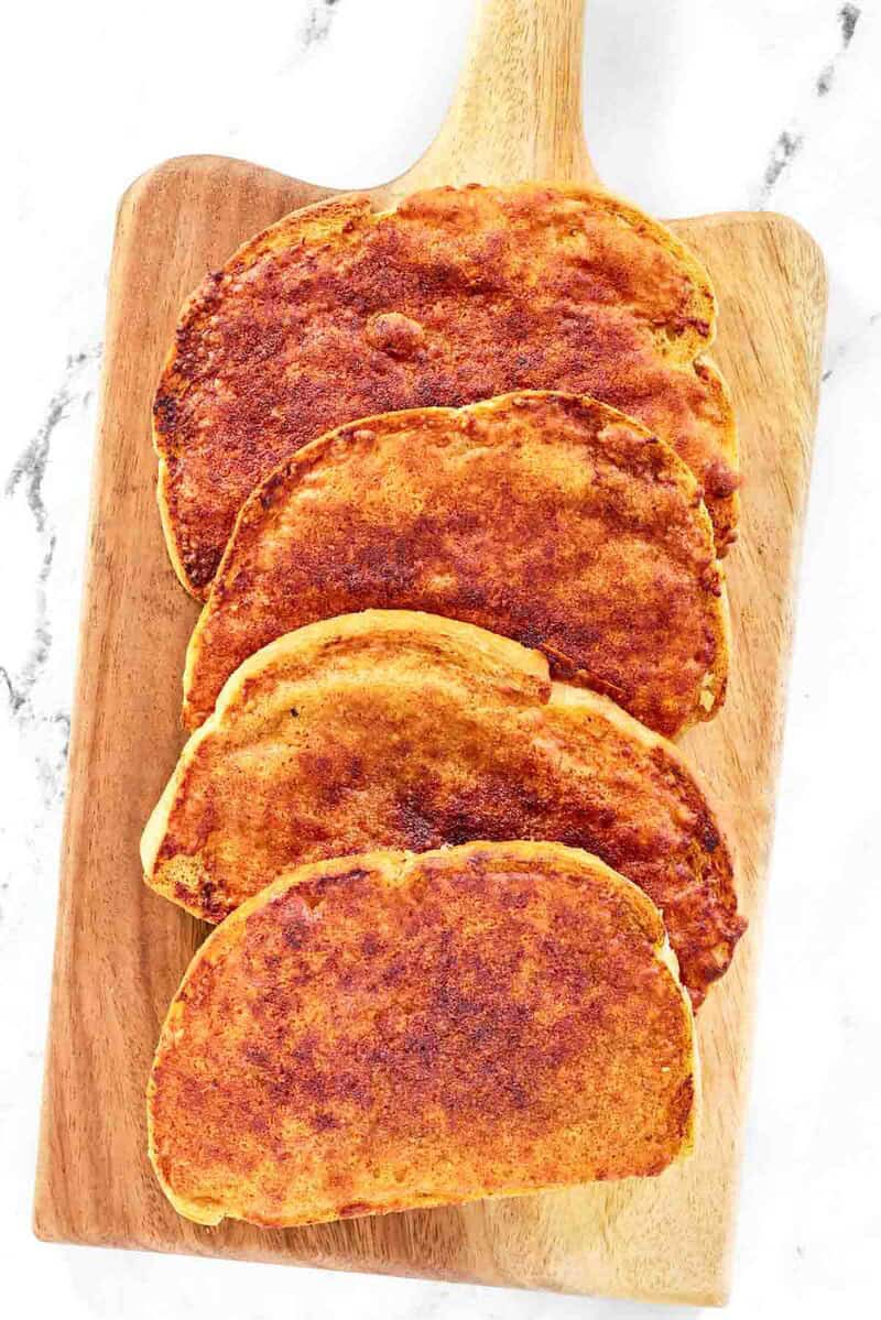 Four slices of North Woods Inn garlic cheese bread with a toasted, bubbly cheese topping, fanned out on a wooden board.