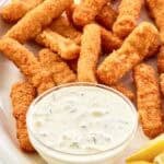 Copycat Skippers tartar sauce in a small bowl, fried fish sticks, and lemon wedges.