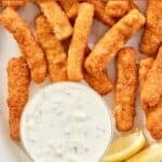 Homemade Skippers tartar sauce in a bowl, lemon wedges, and fried fish sticks.