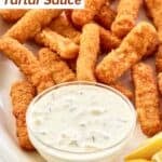 A small bowl of Skippers tartar sauce, fish stick, and lemon wedges.