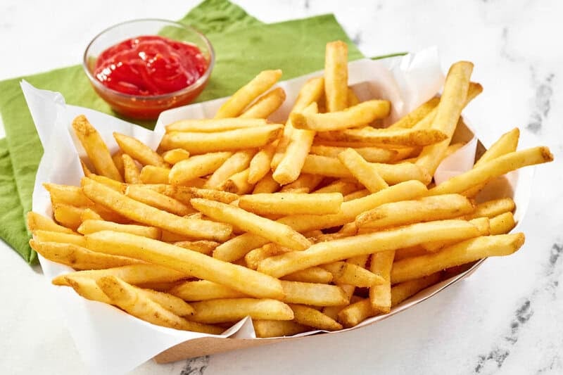 Copycat Wingstop seasoned French fries in a paper serving basket on a marble surface.